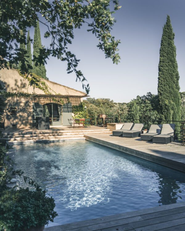 Serene villa pool with lounge chairs and lush greenery on a sunny day, perfect for relaxation and outdoor enjoyment.